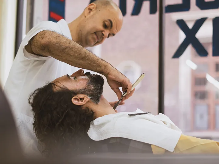 Professional barber giving a real straight-razor beard shave